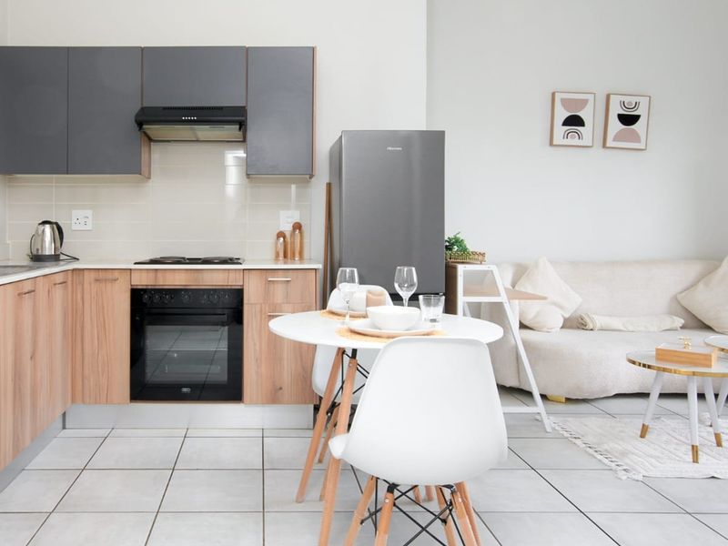 Modern open-plan living area featuring a well-appointed kitchen with built-in cabinetry, oven, hob, and extractor fan, seamlessly flowing into the lounge space.