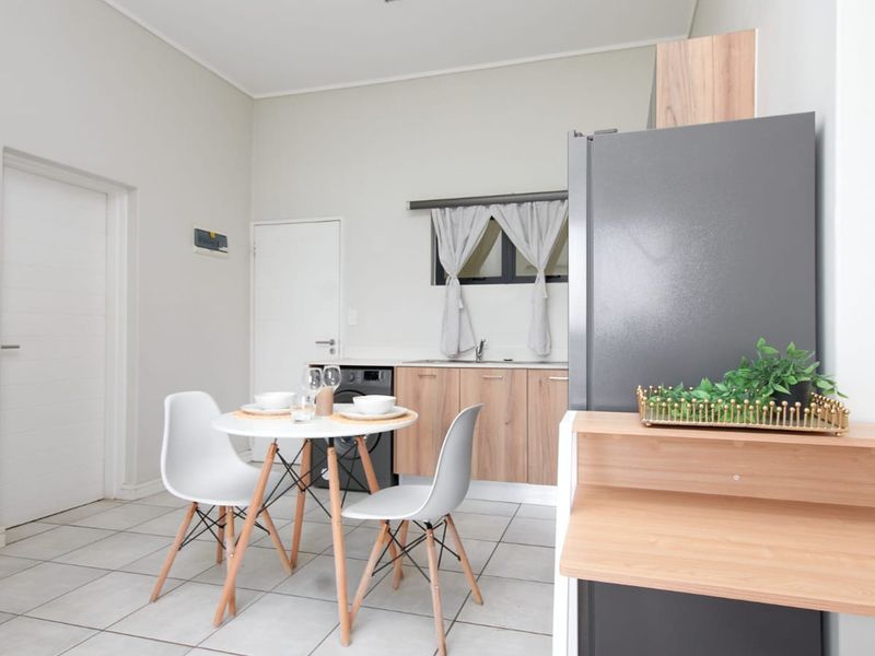 Open plan kitchen and dining area featuring tiled flooring, modern wood-finish cabinetry, and integrated plumbing for laundry appliances.