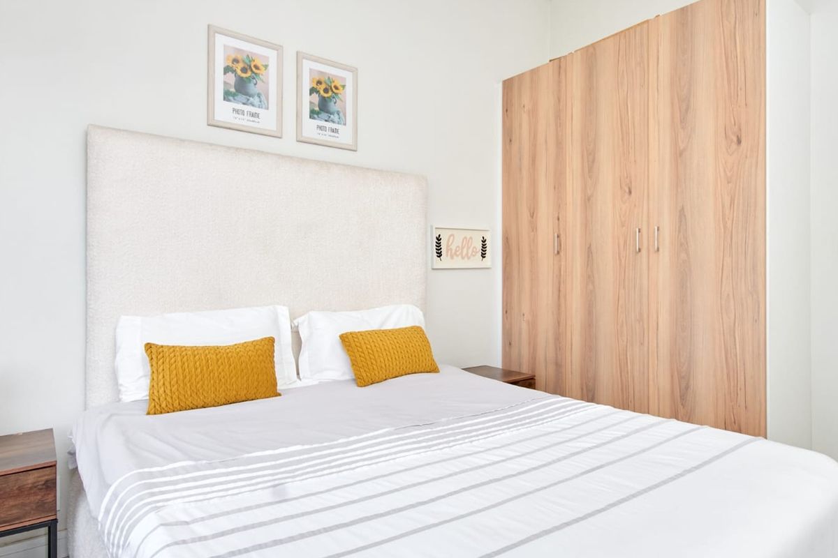 A well-maintained bedroom featuring light wood-finish built-in wardrobes and neutral wall tones, providing a clean and functional living space.