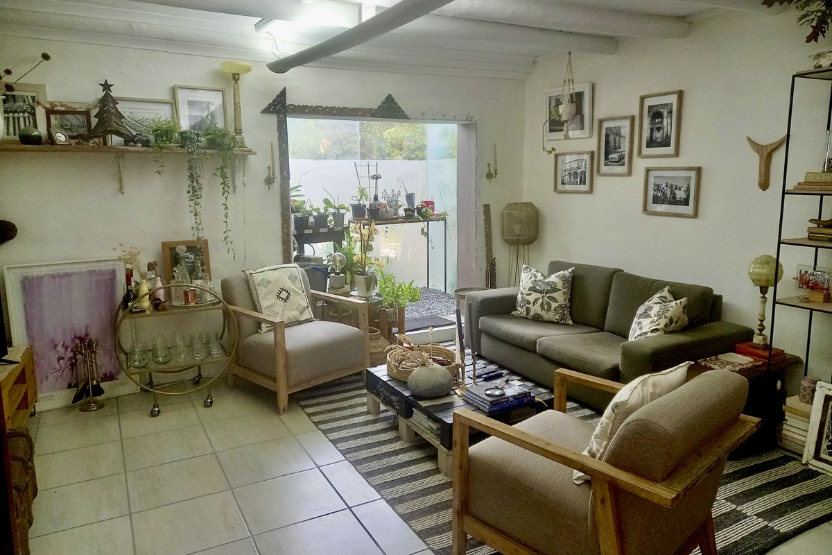 A cozy living room featuring tiled flooring, exposed ceiling beams, and direct access to an outdoor patio area.
