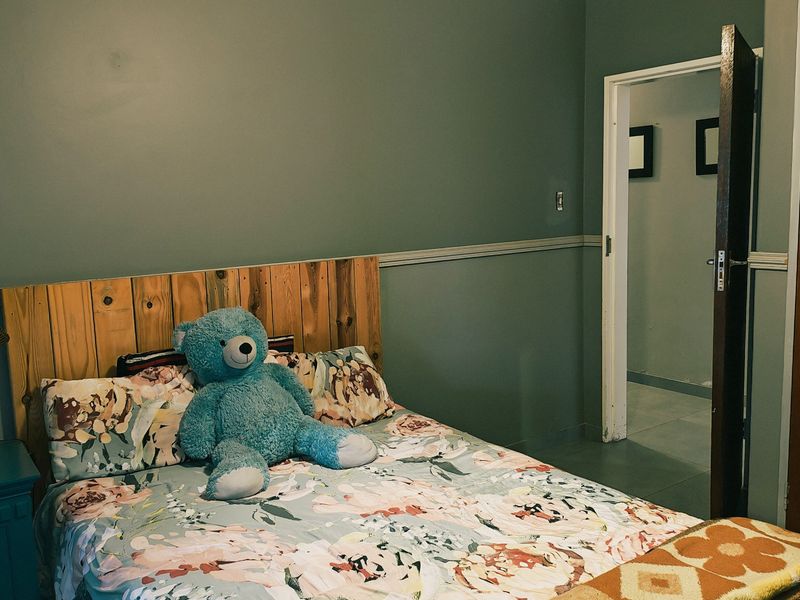 A bedroom featuring a wooden headboard, chair rail molding, and a doorway leading to an adjacent space.