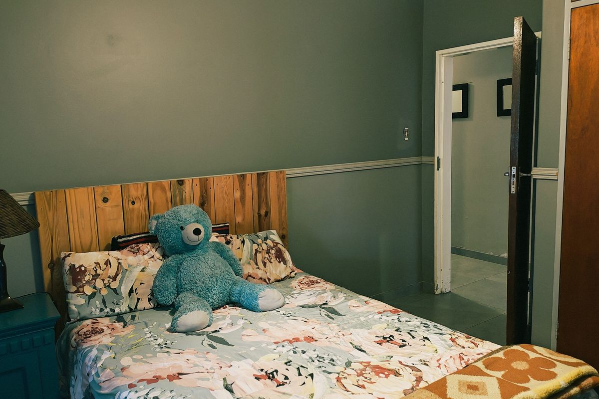 A bedroom featuring a wooden headboard, chair rail molding, and a doorway leading to an adjacent space.