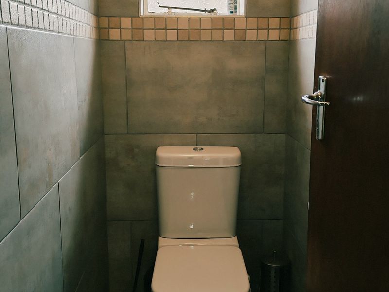 A compact, tiled bathroom featuring a modern toilet and a small high-level window for ventilation.