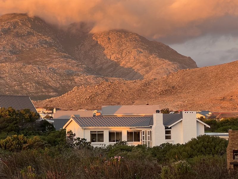 A scenic view of a residential property set against a dramatic mountain backdrop during sunset.