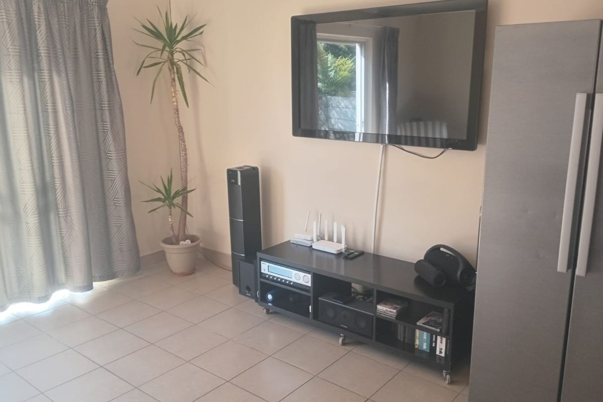 A living room area featuring neutral tiled flooring and a sliding door providing access to the exterior.