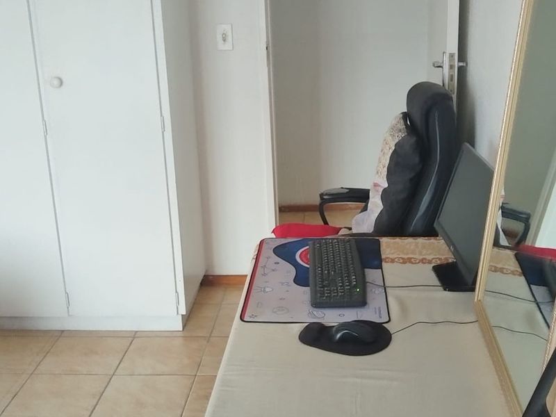 A bedroom featuring tiled flooring and a built-in wardrobe, currently utilized as a workspace.