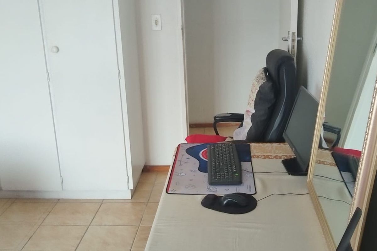 A bedroom featuring tiled flooring and a built-in wardrobe, currently utilized as a workspace.