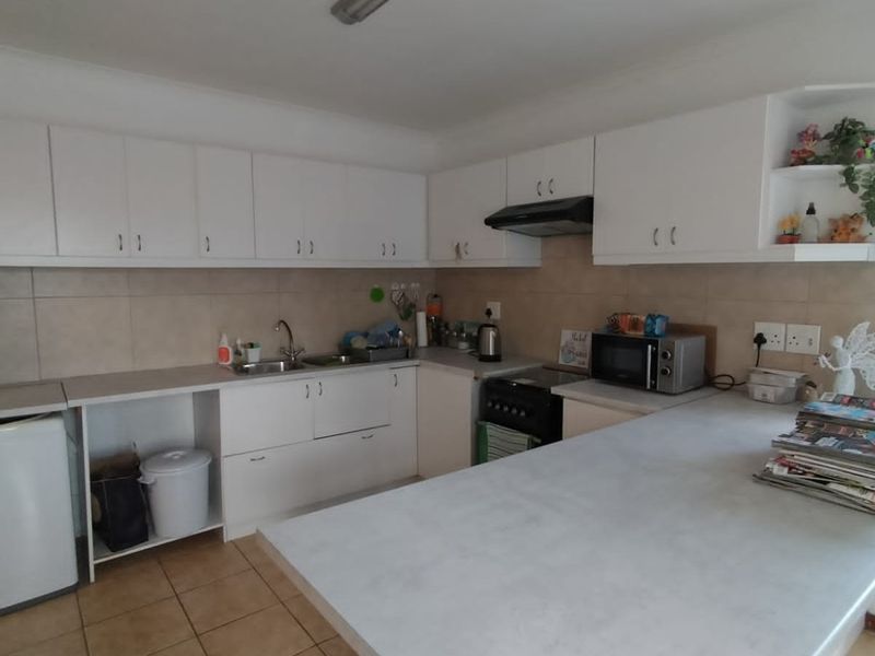 A functional kitchen featuring white built-in cabinetry, laminate countertops, a tiled backsplash, and a breakfast bar area.