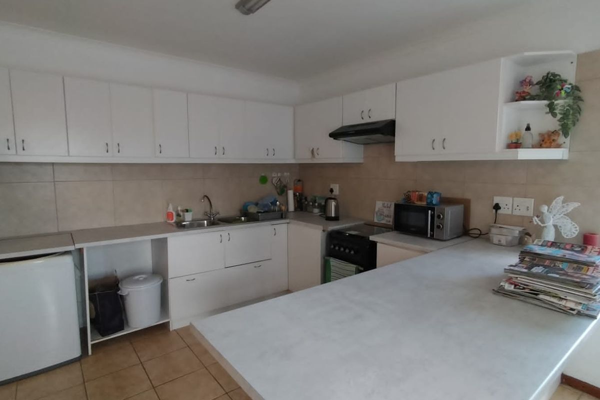 A functional kitchen featuring white built-in cabinetry, laminate countertops, a tiled backsplash, and a breakfast bar area.
