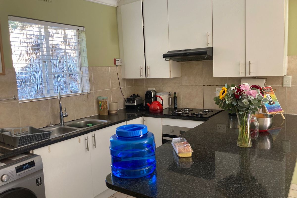 Functional kitchen featuring granite countertops, white cabinetry, built-in oven, gas hob, extractor fan, and a double basin sink with integrated laundry space.