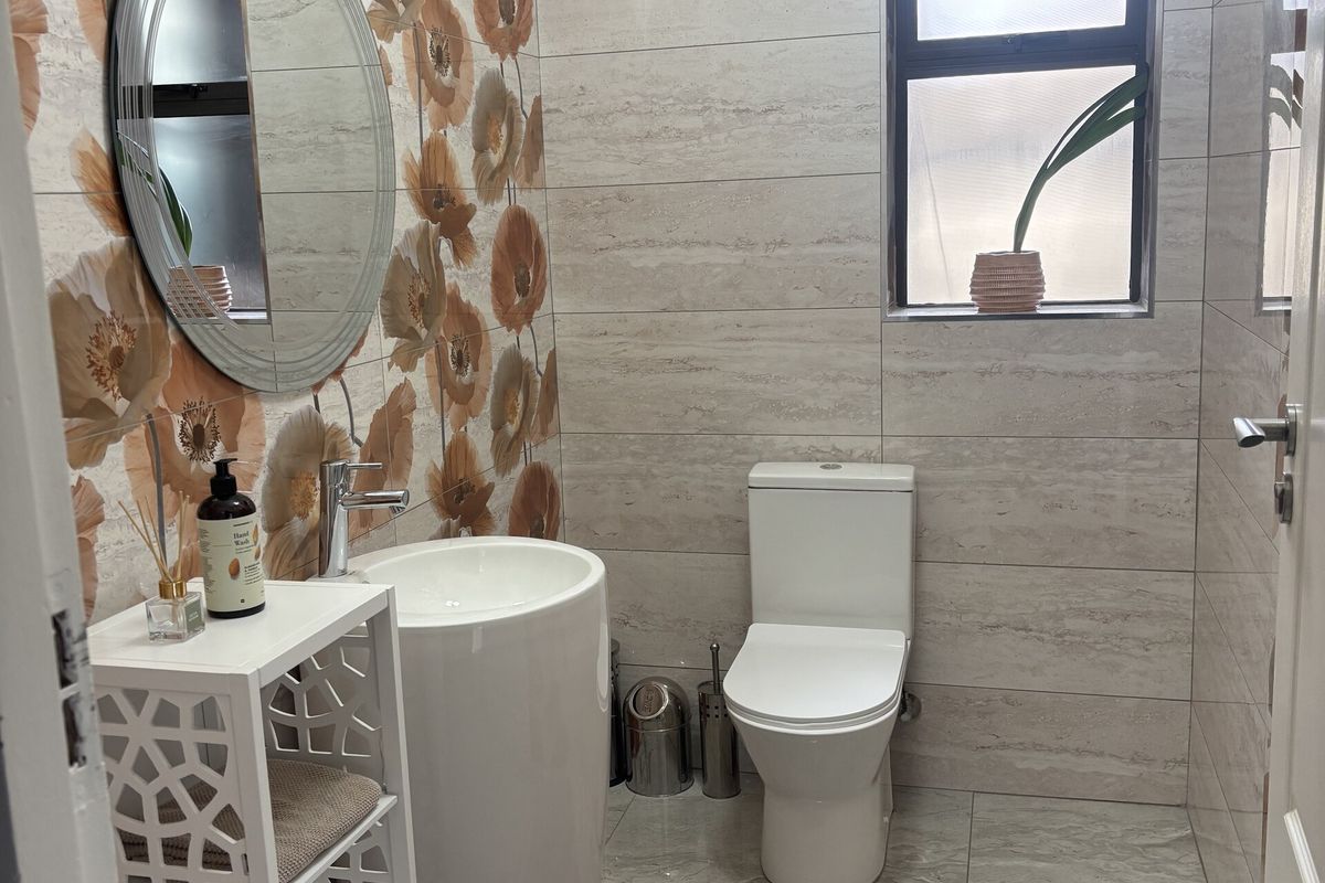 A modern guest bathroom featuring a pedestal basin, toilet, and decorative floral-patterned wall tiles.