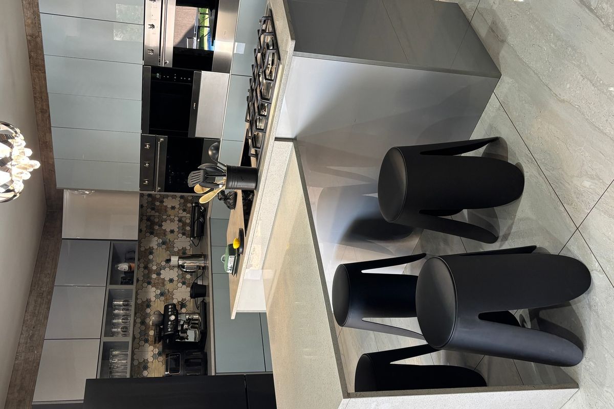 Modern kitchen featuring high-gloss cabinetry, stone countertops, a gas hob, built-in oven, and decorative tiled splashback with large format floor tiles.