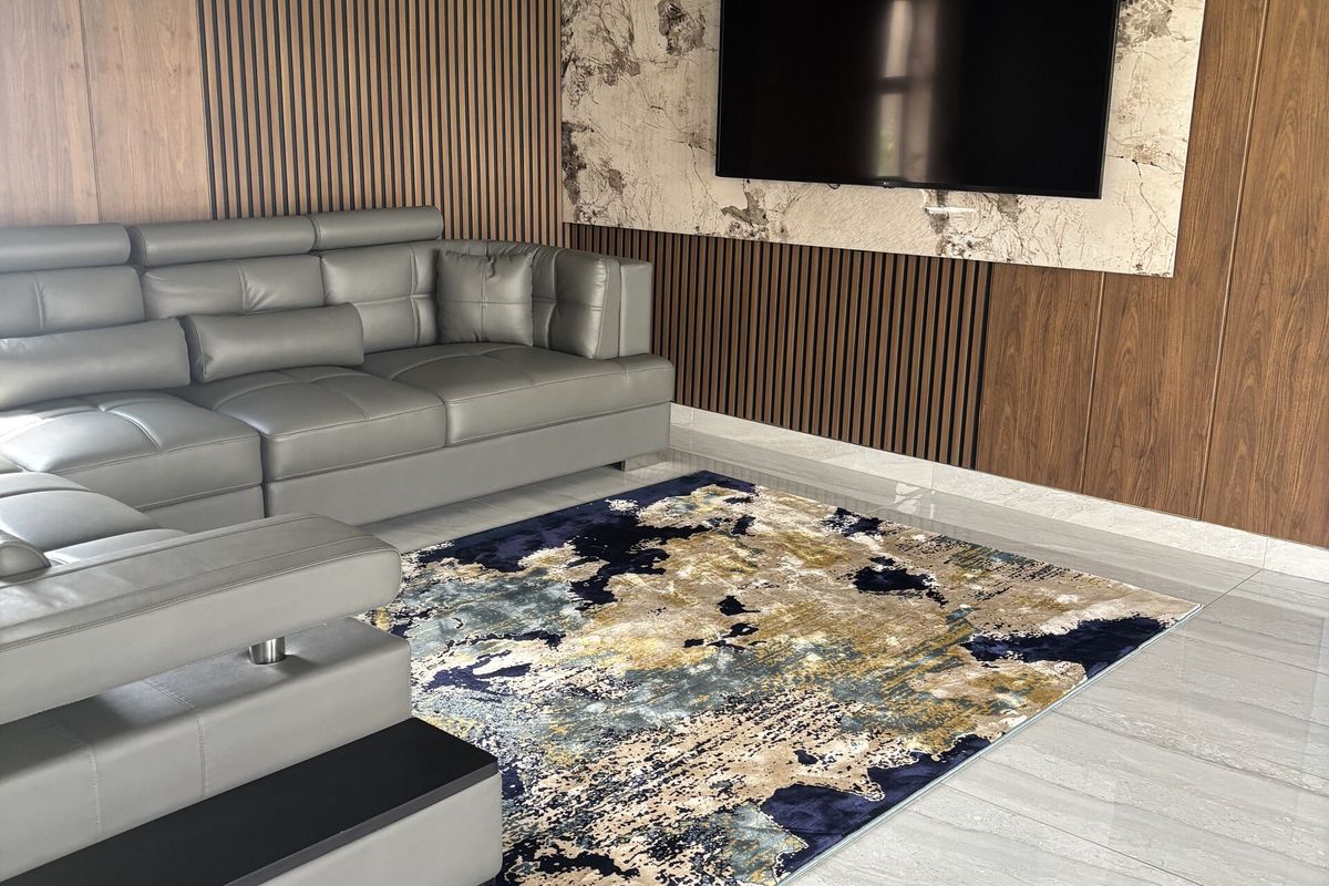 A modern living room featuring sophisticated slatted wood wall paneling, a marble-effect TV feature wall, and polished porcelain floor tiles.