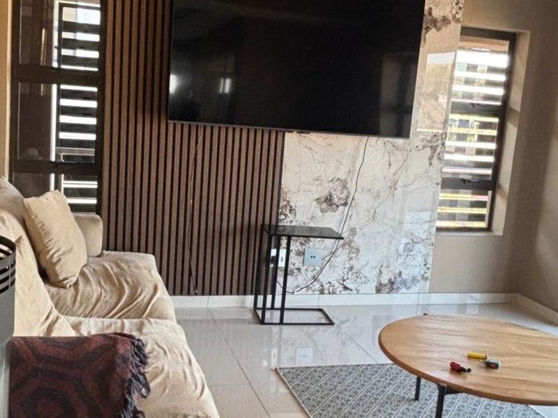 Modern living room featuring a stylish slatted timber and marble-look feature wall, tiled flooring, and a contemporary freestanding fireplace.