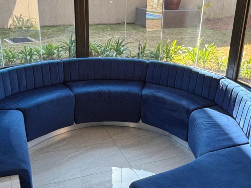 A bright, enclosed patio area featuring large glass panels and tiled flooring, offering a seamless view of the garden.