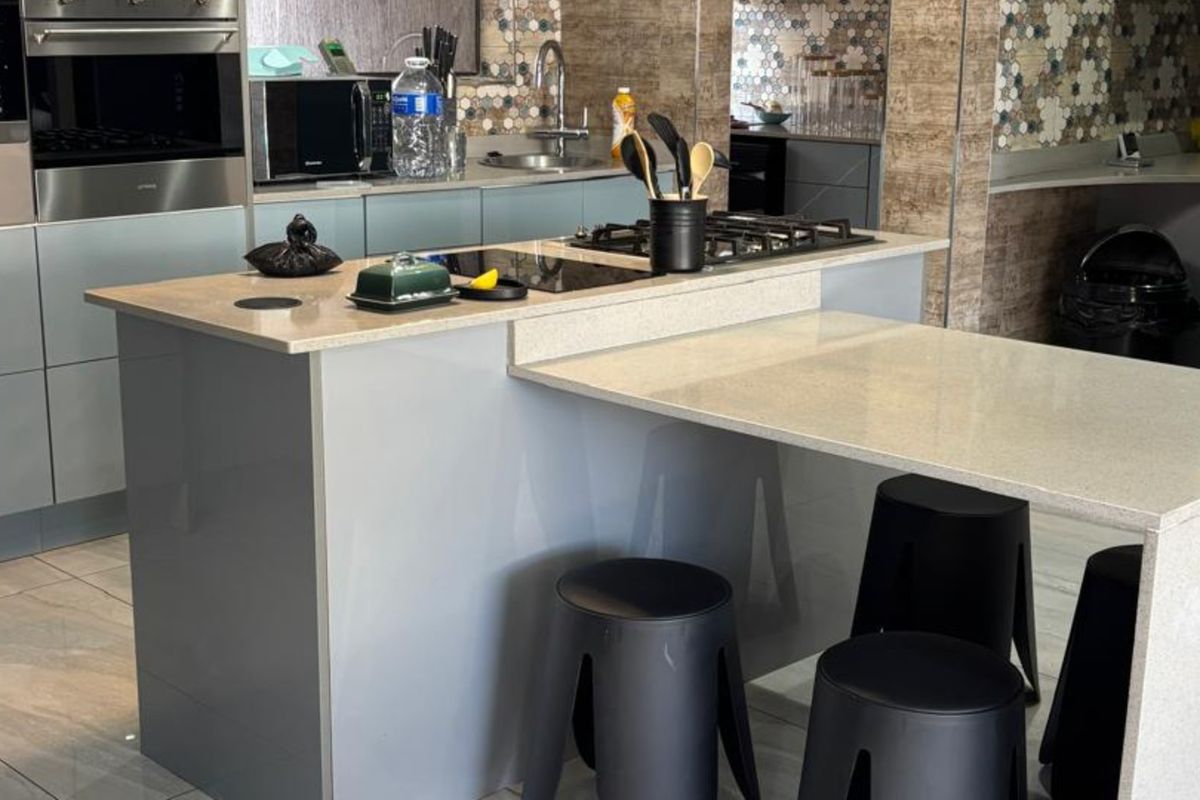 Modern kitchen featuring a central island with a built-in gas hob, stone countertops, and contemporary cabinetry with a decorative tiled backsplash.