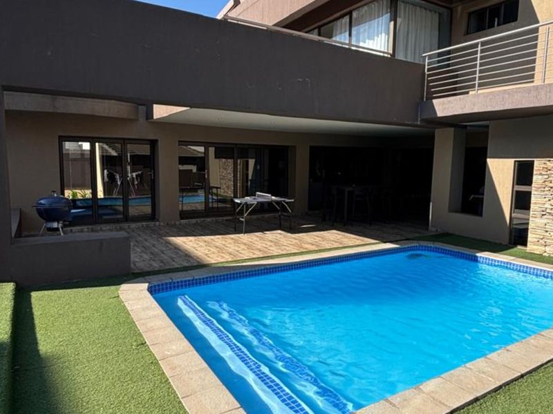 Outdoor entertainment area featuring a swimming pool, covered patio with tiled flooring, and stone-clad exterior wall accents.