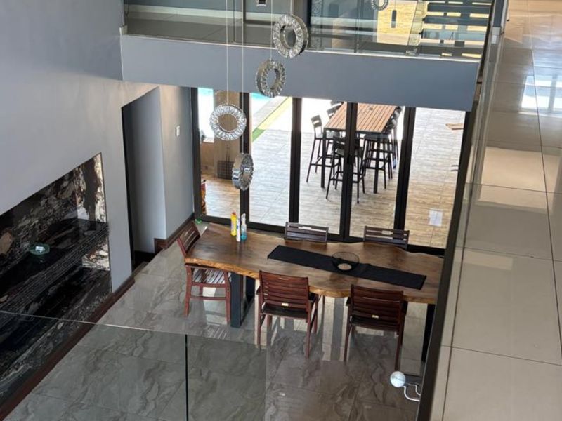 Spacious open-plan dining area featuring large format floor tiles, a modern built-in fireplace, and seamless bi-fold doors opening to an outdoor patio.