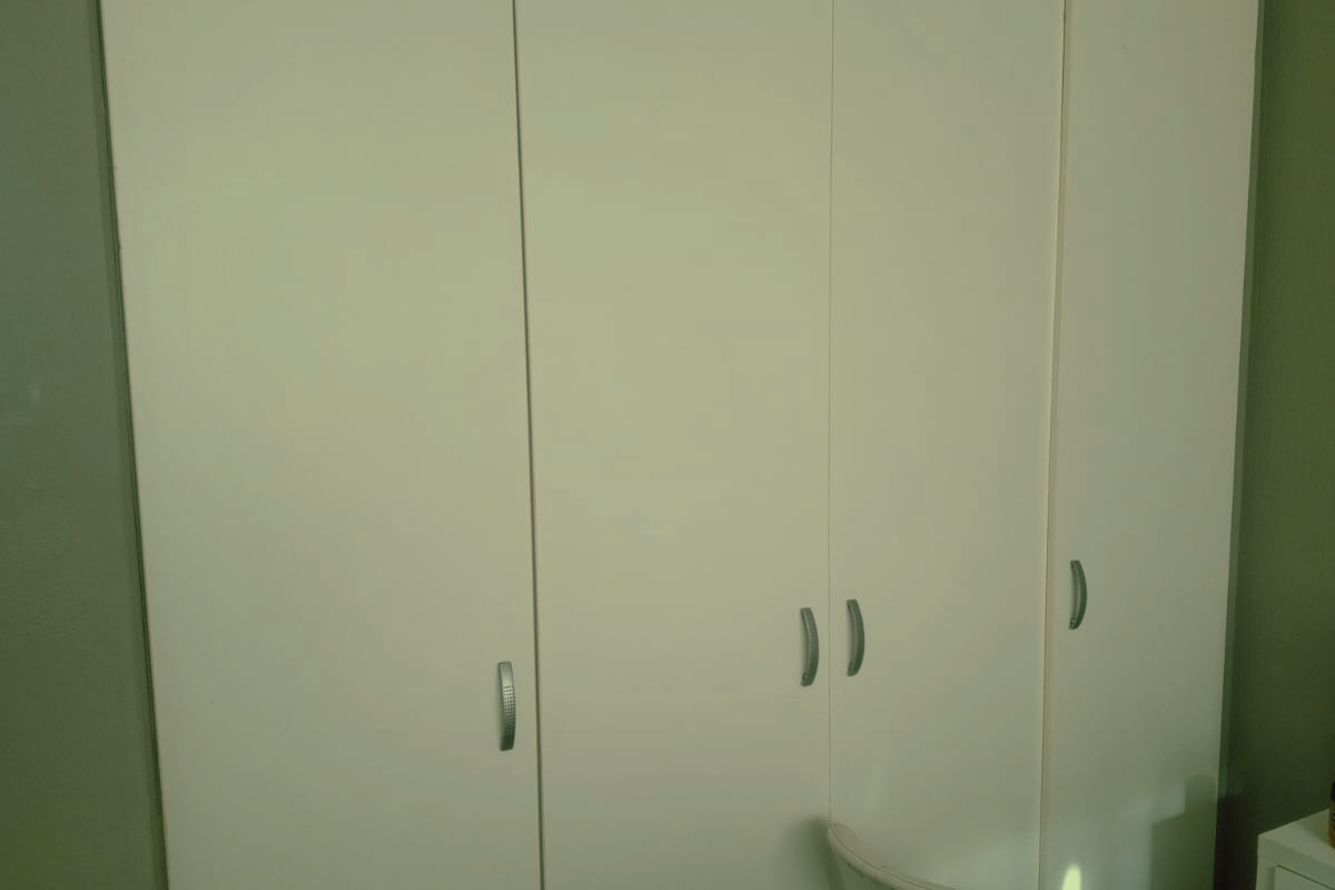 A bedroom featuring floor-to-ceiling built-in cupboards providing ample storage space.
