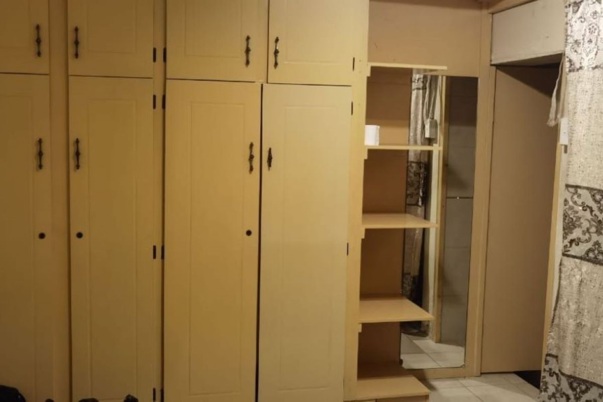 A bedroom featuring extensive built-in floor-to-ceiling cabinetry with integrated shelving and a full-length mirror.