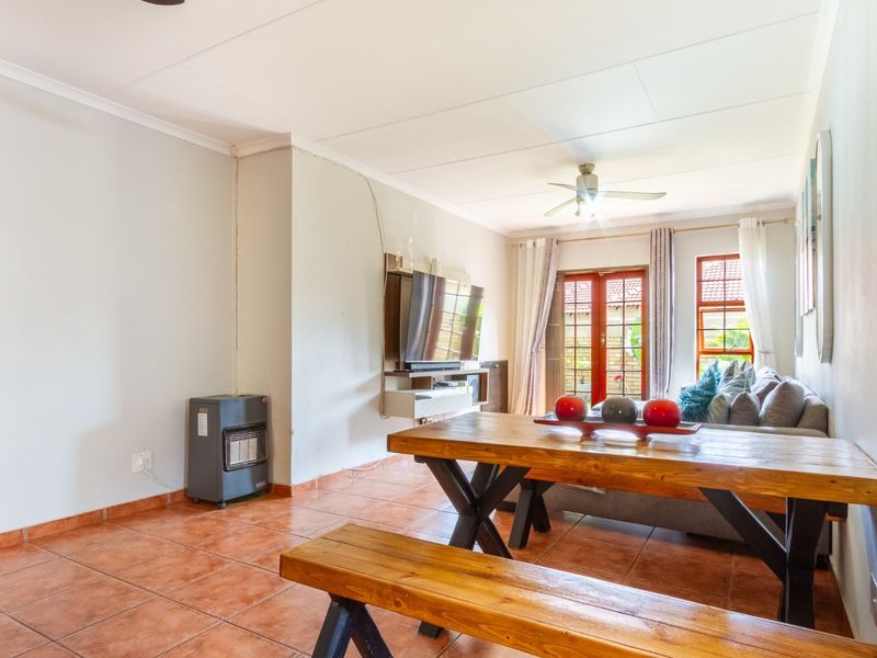Open-plan living and dining area featuring terracotta floor tiles, a ceiling fan, and direct access to the outdoor space through double glass doors.