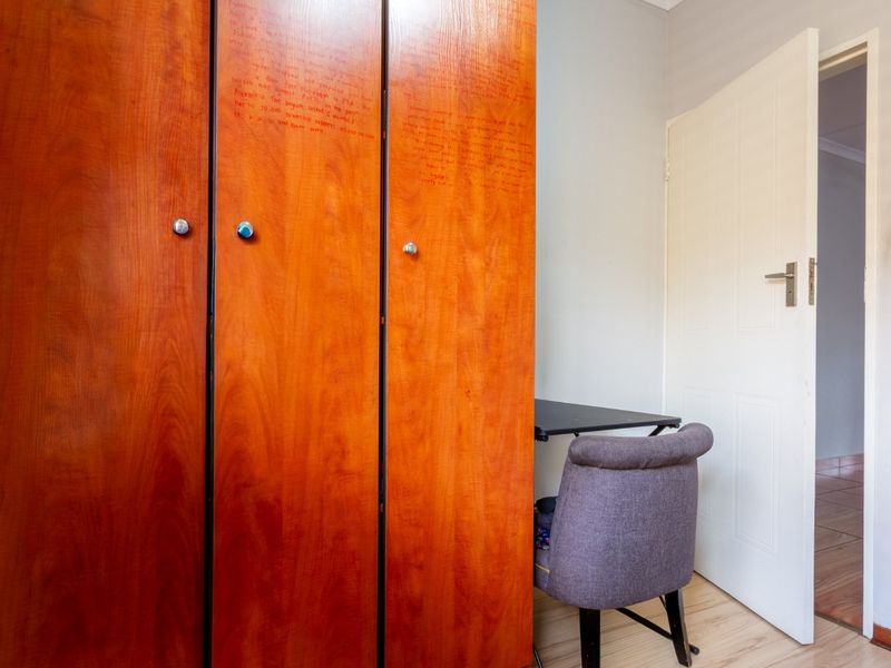 A bedroom featuring built-in wooden wardrobes and laminate flooring, requiring cosmetic updates to the cabinetry.
