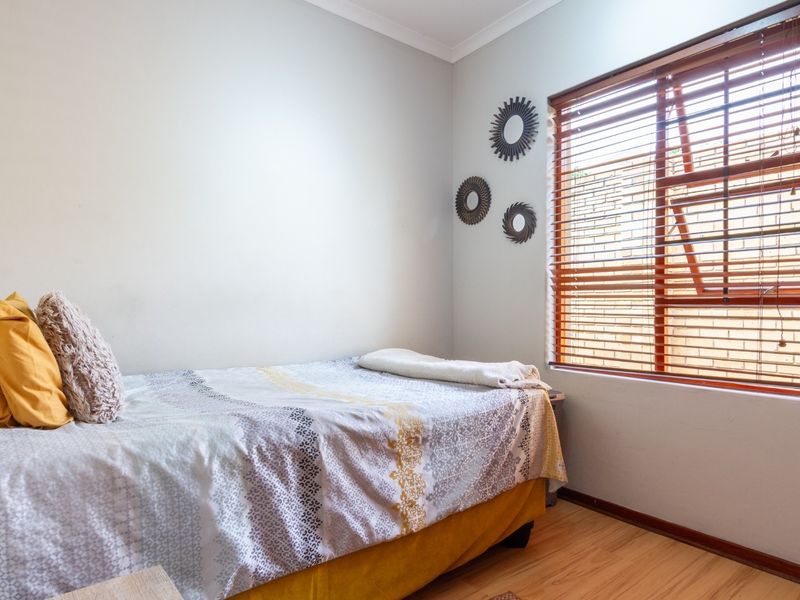 A functional bedroom featuring laminate flooring and timber venetian blinds, providing a neutral space ready for personalization.