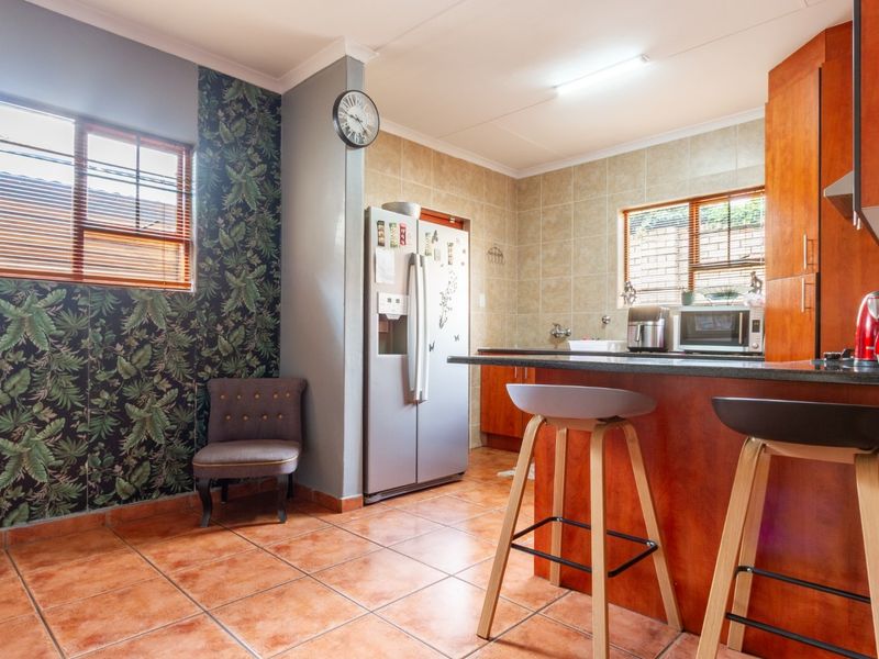 A functional kitchen featuring wooden cabinetry, granite countertops, a breakfast bar, and tiled flooring, offering a practical layout for daily meal preparation.
