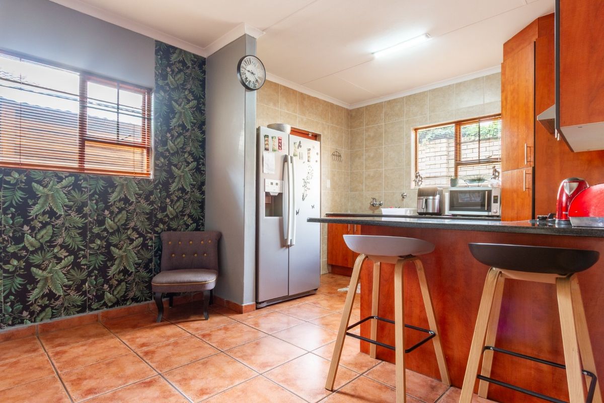 A functional kitchen featuring wooden cabinetry, granite countertops, a breakfast bar, and tiled flooring, offering a practical layout for daily meal preparation.