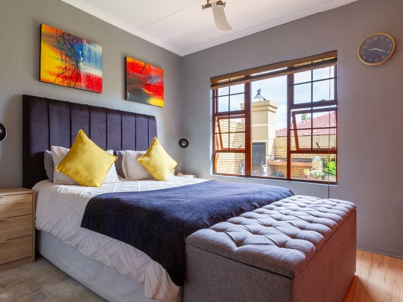 A well-maintained bedroom featuring grey walls, a built-in wardrobe, a ceiling fan, and a window with wooden blinds overlooking the exterior area.