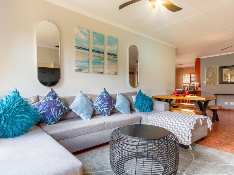 Open-plan living area featuring tiled flooring, ceiling fans, and coved cornicing, creating a connected space between the lounge and dining area.
