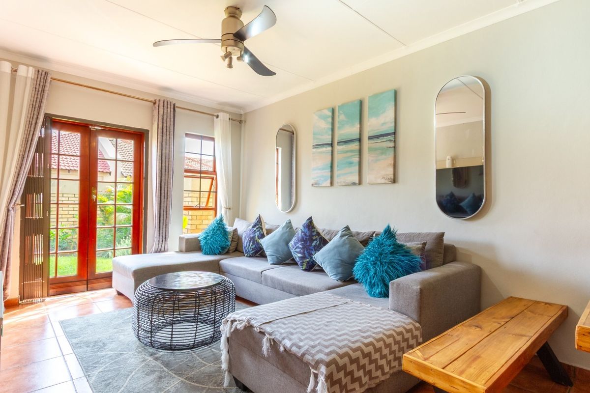 A bright living room featuring tiled flooring, a ceiling fan, and french doors providing access to the outdoor area.