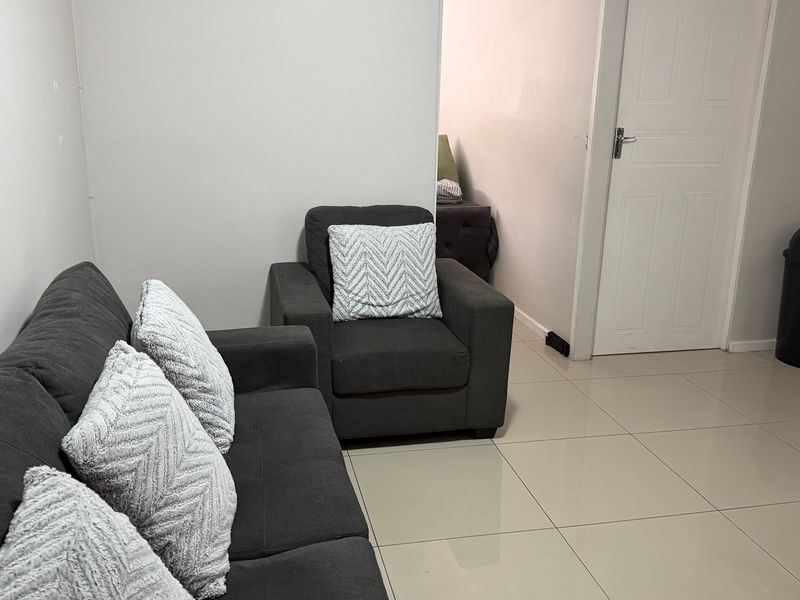 A living room area featuring neutral tiled flooring and a standard interior door, providing a clean and functional space.
