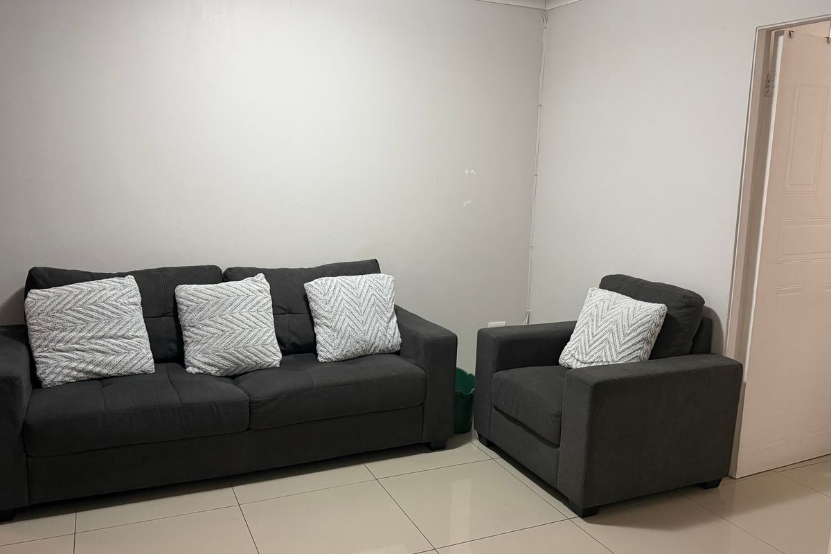 A simple living room area featuring neutral tiled flooring and plain walls, providing a functional and blank canvas for interior design.
