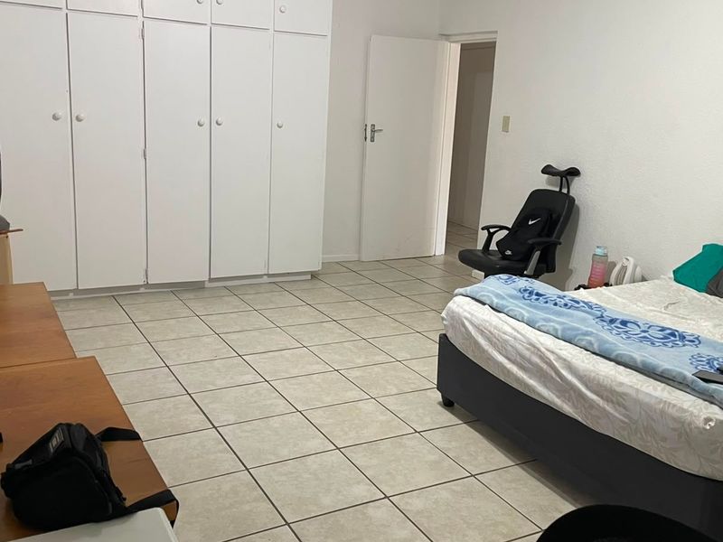 A bedroom featuring tiled flooring and extensive built-in cupboard storage.