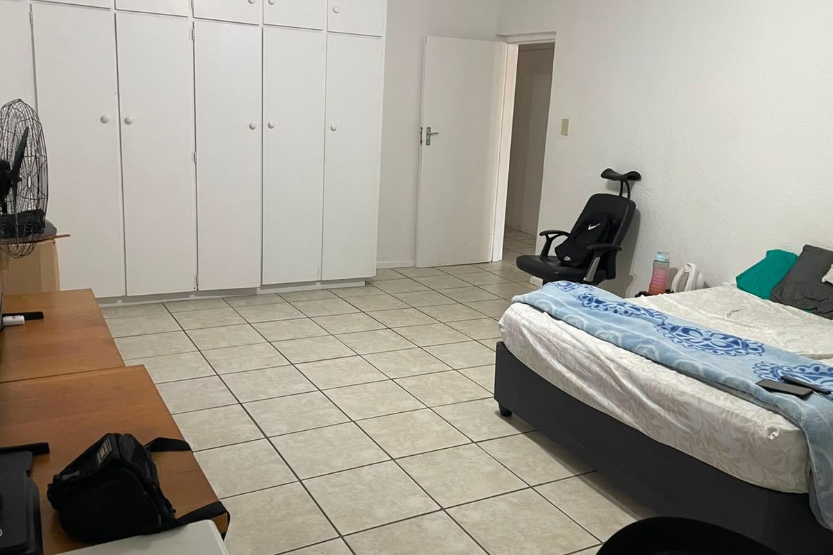 A bedroom featuring tiled flooring and extensive built-in cupboard storage.
