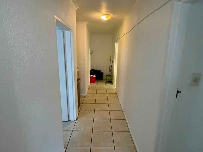 A functional hallway featuring neutral tiled flooring and access to multiple rooms, providing a clean and simple transition space within the apartment.