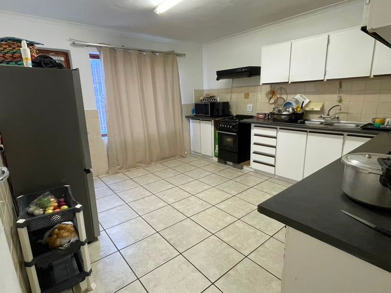 Functional kitchen featuring white cabinetry, laminate countertops, a tiled backsplash, and a freestanding stove with an extractor fan.