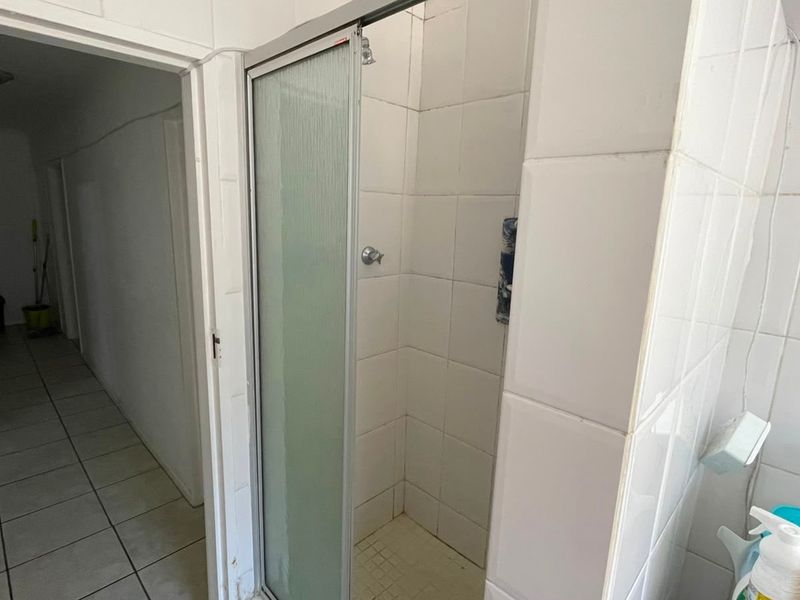 A functional bathroom featuring a tiled shower enclosure with a glass door, requiring some cosmetic updates to the finishes.