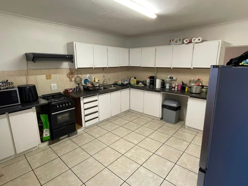 Functional kitchen featuring white built-in cabinetry, laminate countertops, tiled flooring, and a freestanding stove with an extractor fan.