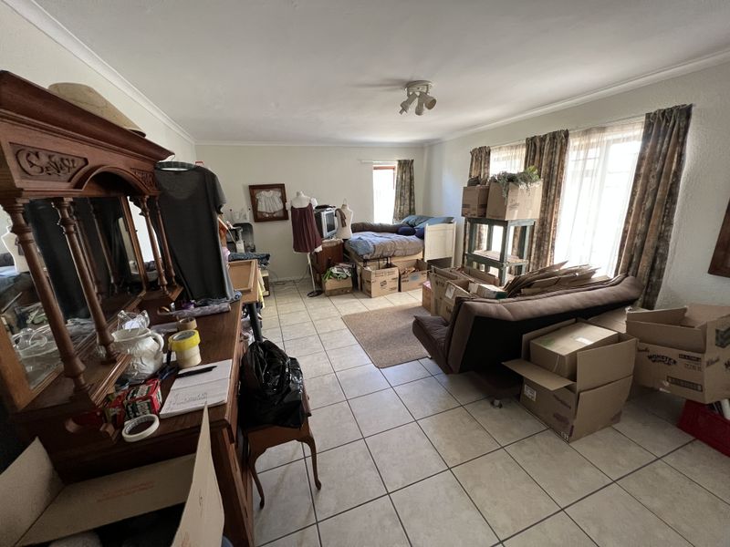 A spacious living area featuring neutral ceramic floor tiles and large sliding glass doors that provide ample natural light.