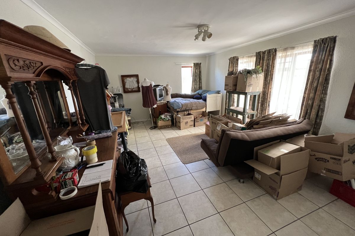 A spacious living area featuring neutral ceramic floor tiles and large sliding glass doors that provide ample natural light.