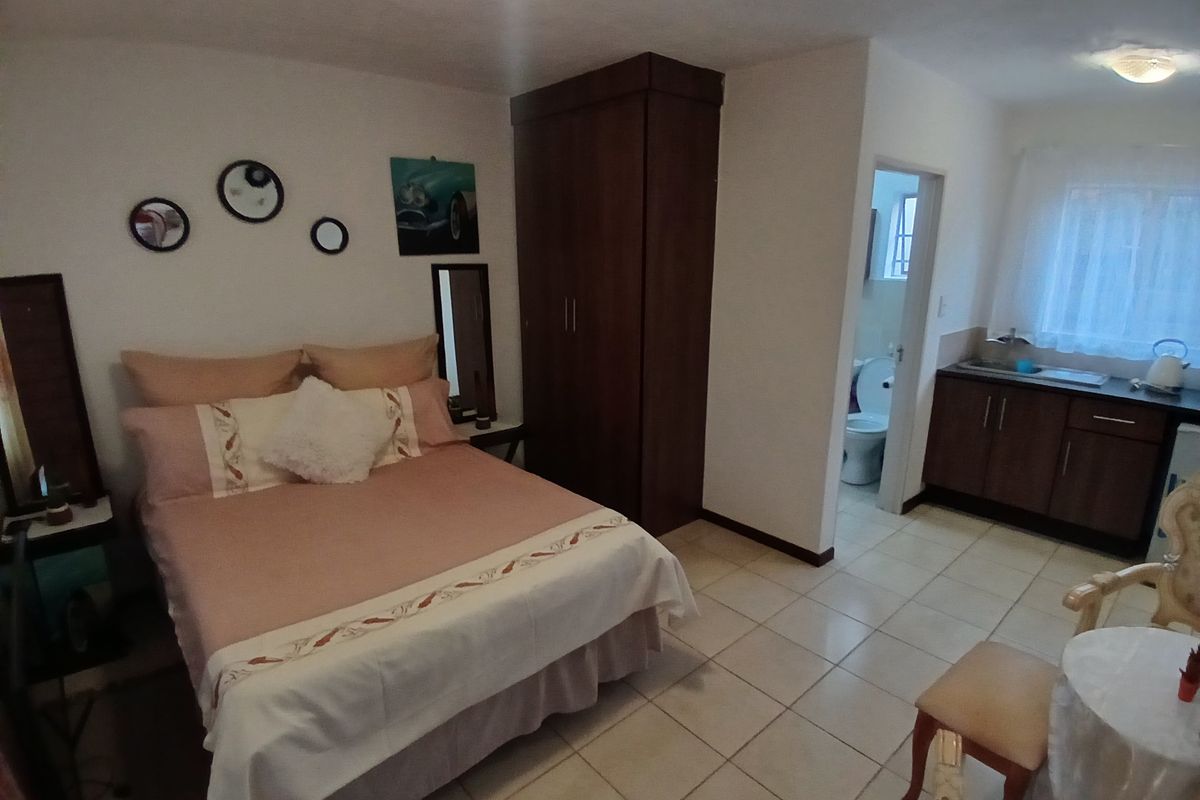 A bedroom featuring tiled flooring, a built-in wardrobe, and an adjoining kitchenette and en-suite bathroom.