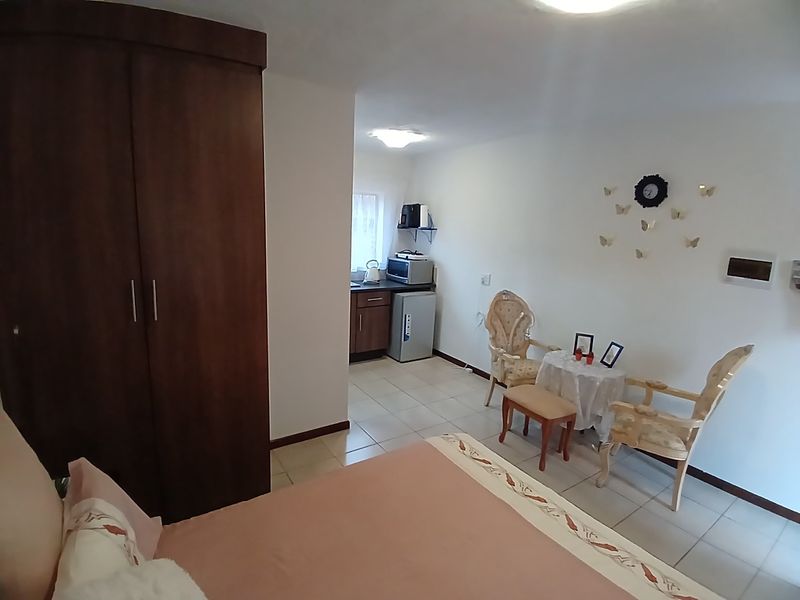 Open-plan studio apartment featuring a built-in wardrobe, tiled flooring, and a compact kitchenette area.