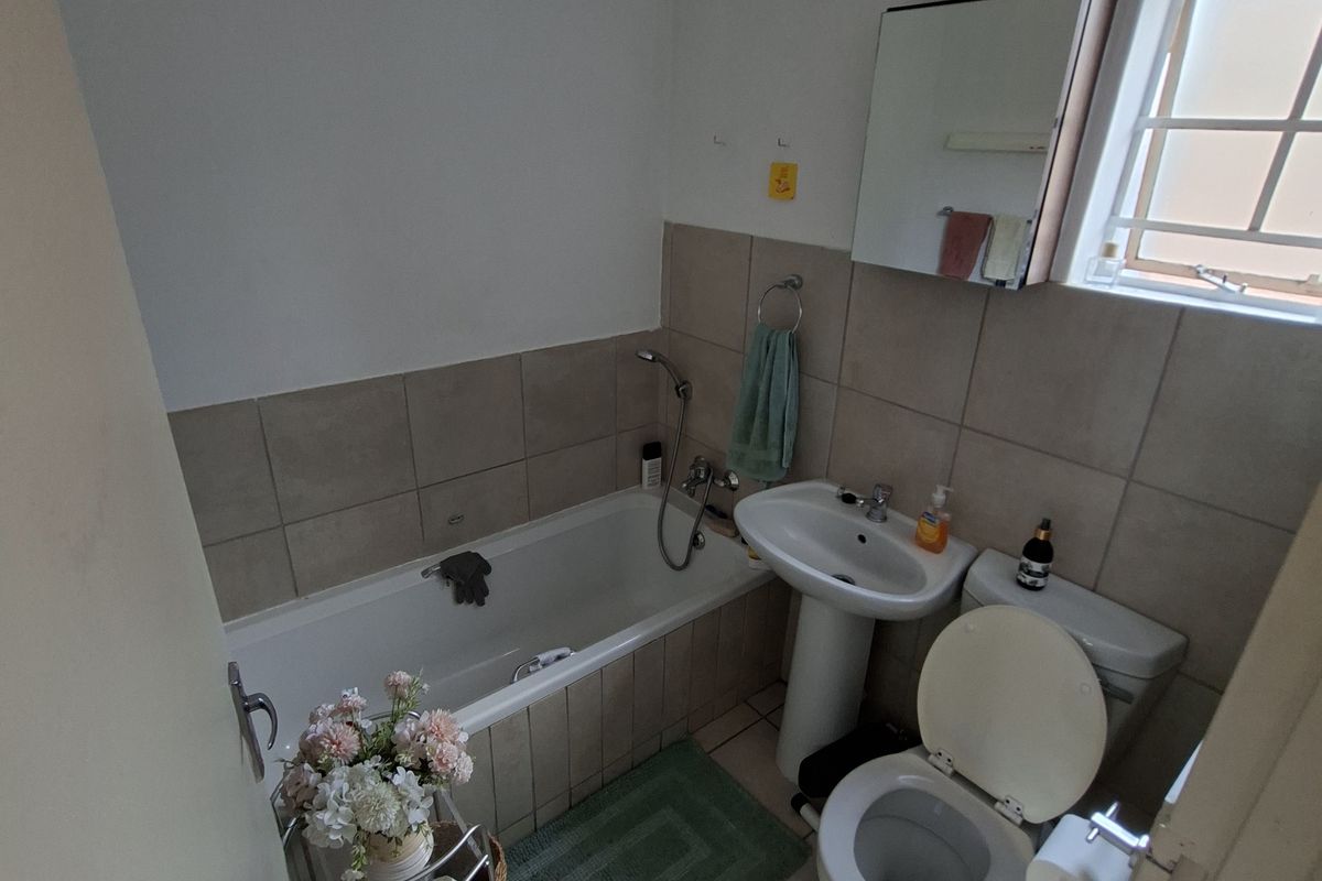 A functional bathroom featuring a bathtub, pedestal sink, toilet, and tiled finishes, offering a practical layout for daily use.