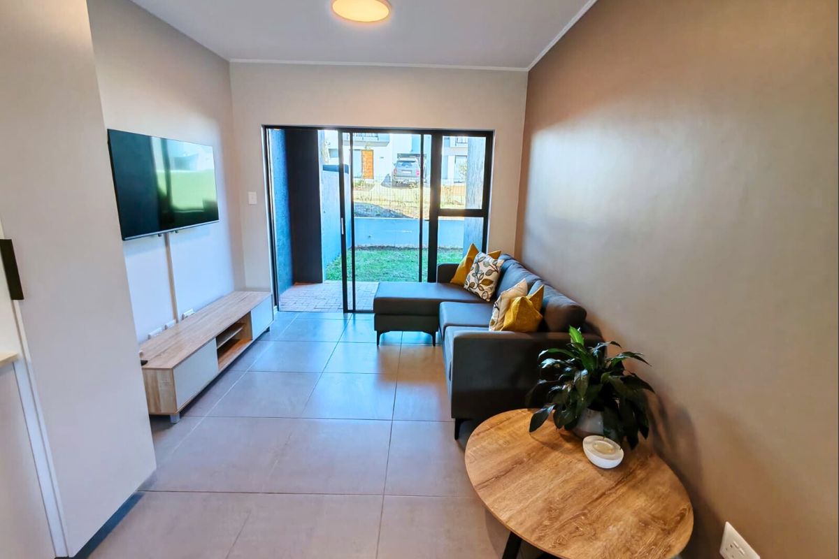 A modern living room featuring large format floor tiles and a sliding glass door providing direct access to the outdoor patio area.