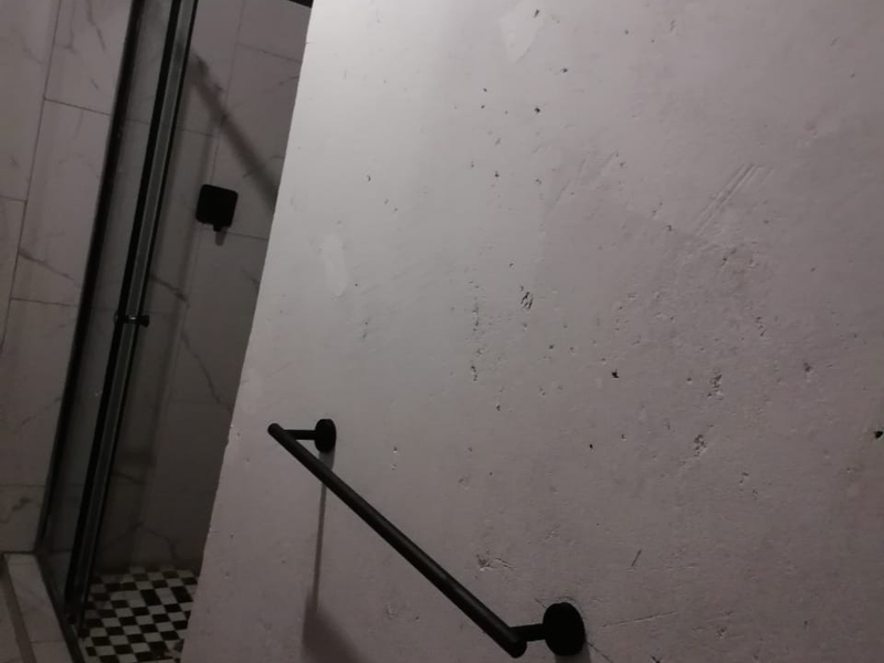 A bathroom under renovation featuring a shower enclosure, black towel rail, and tiled flooring, with unfinished wall surfaces requiring completion.