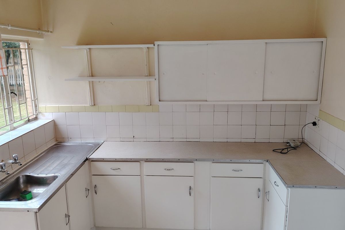 A functional kitchen space featuring white cabinetry, laminate countertops, and a stainless steel sink, ready for a modern renovation or update.