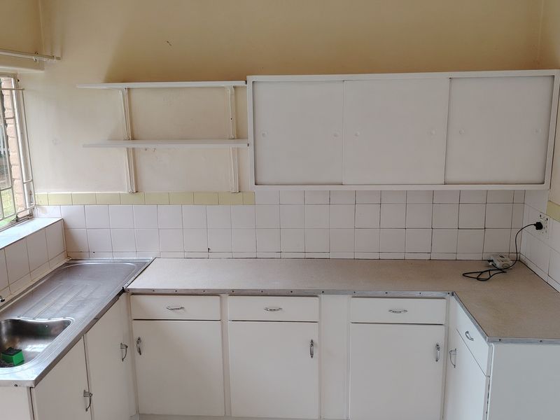 A functional kitchen space featuring white cabinetry, laminate countertops, and a stainless steel sink, ready for a modern renovation or update.