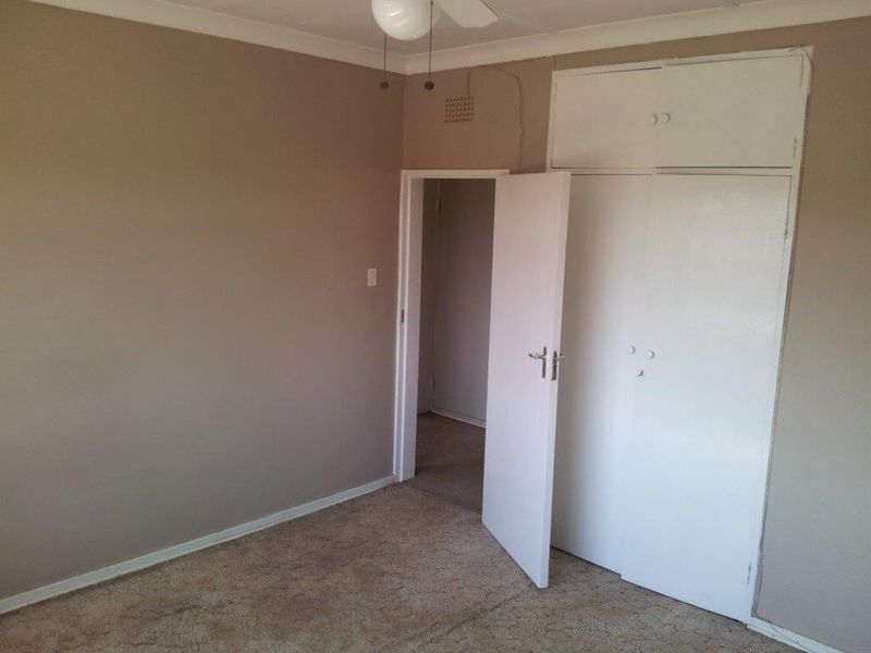 An empty bedroom featuring built-in cupboards, a ceiling fan, and carpeted flooring, offering a blank canvas for personalization.